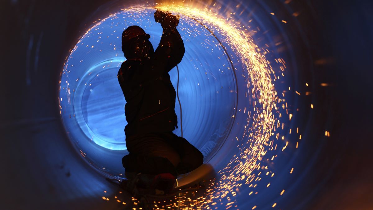 A worker works inside a pipe on a pipeline construction