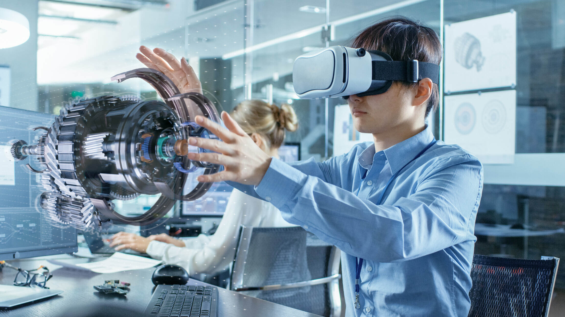 Computer Science Engineer wearing Virtual Reality Headset Works with 3D Model Hologram Visualization, Makes Gestures. In the Background Engineering Bureau with Busy Coworkers. Future of jobs, entrepreneurs