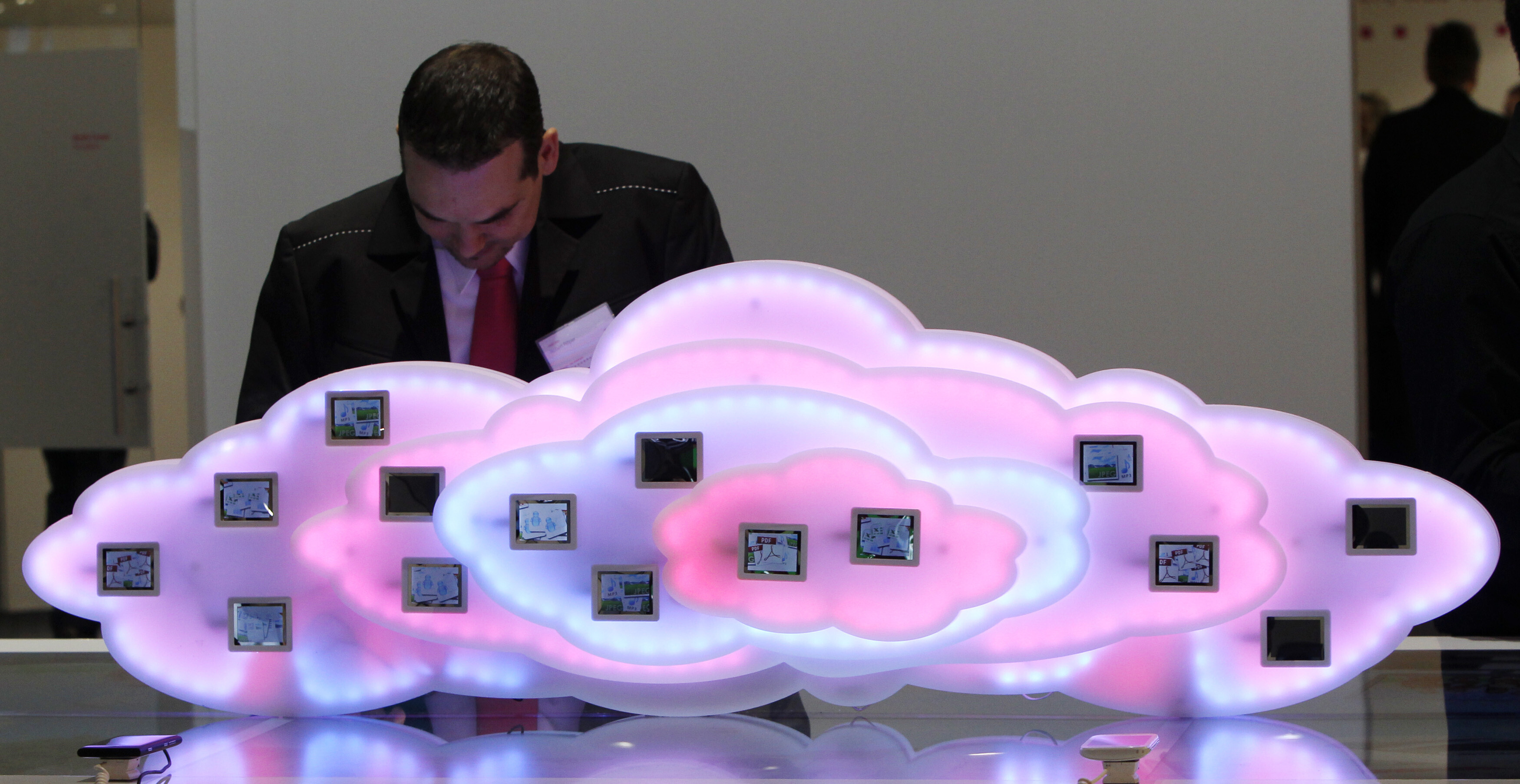 A staff member checks a display to demonstrate cloud computing with mobile phones at the booth of German company Deutsche Telekom during preparations at the CeBit computer fair in Hanover, March, 5, 2012. The biggest fair of its kind open its doors to the public on March 6 and will run to March 10: The biggest new services trade barriers are regulatory differences