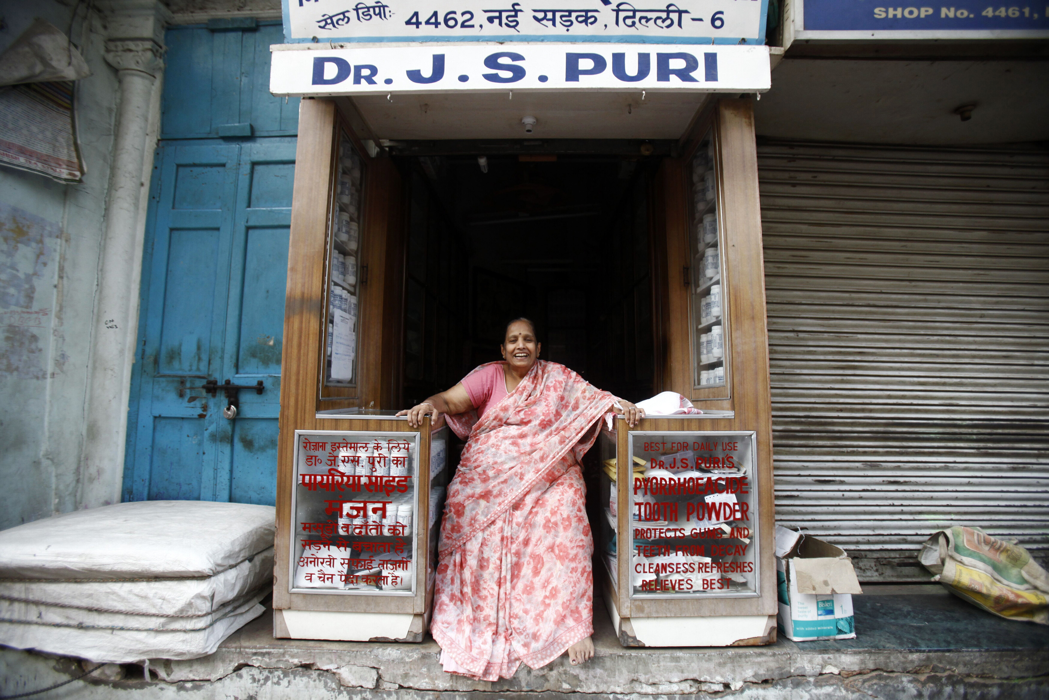 A woman selling tooth powder smiles while sitting at her shop in the old quarters of Delhi April 10, 2013: A digital inclusion social bond could help MSMEs access much needed digital finance