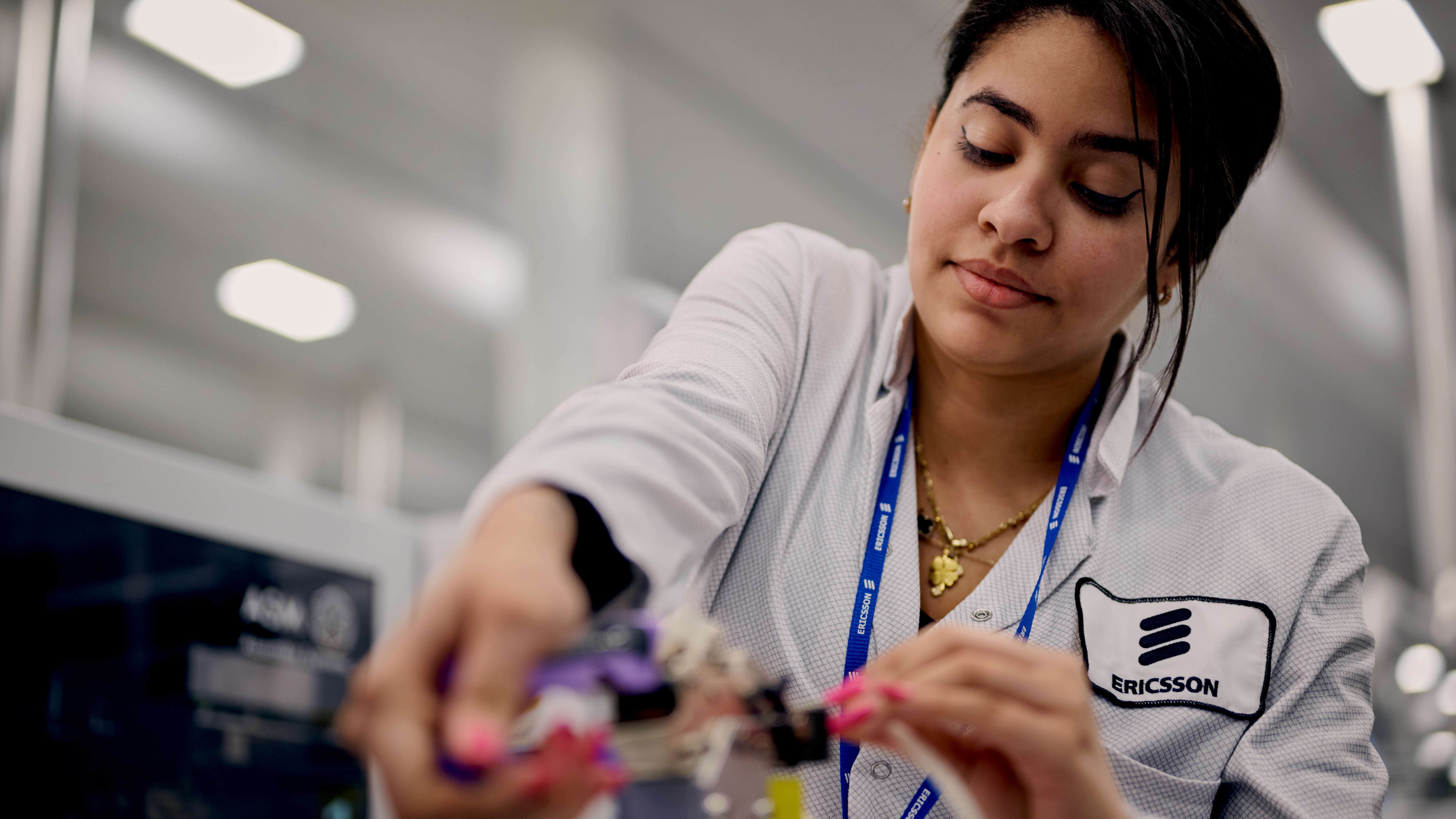 Woman looks at something technical at an Ericsson factory: Including human oversight with automation makes for a more resilient operation